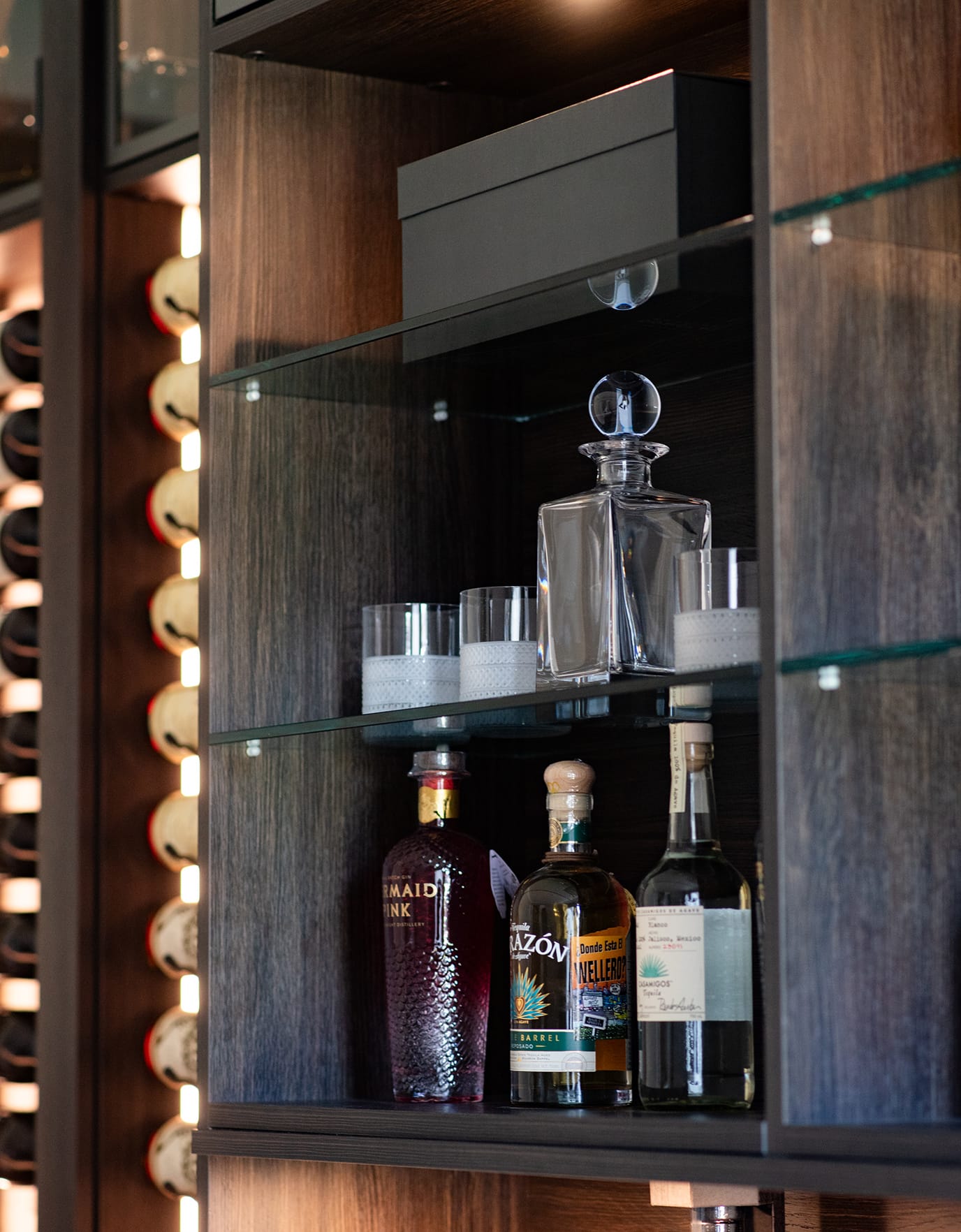Detail of home wine bar shelving with LED lighting and vertical wine racks designed by California Closets