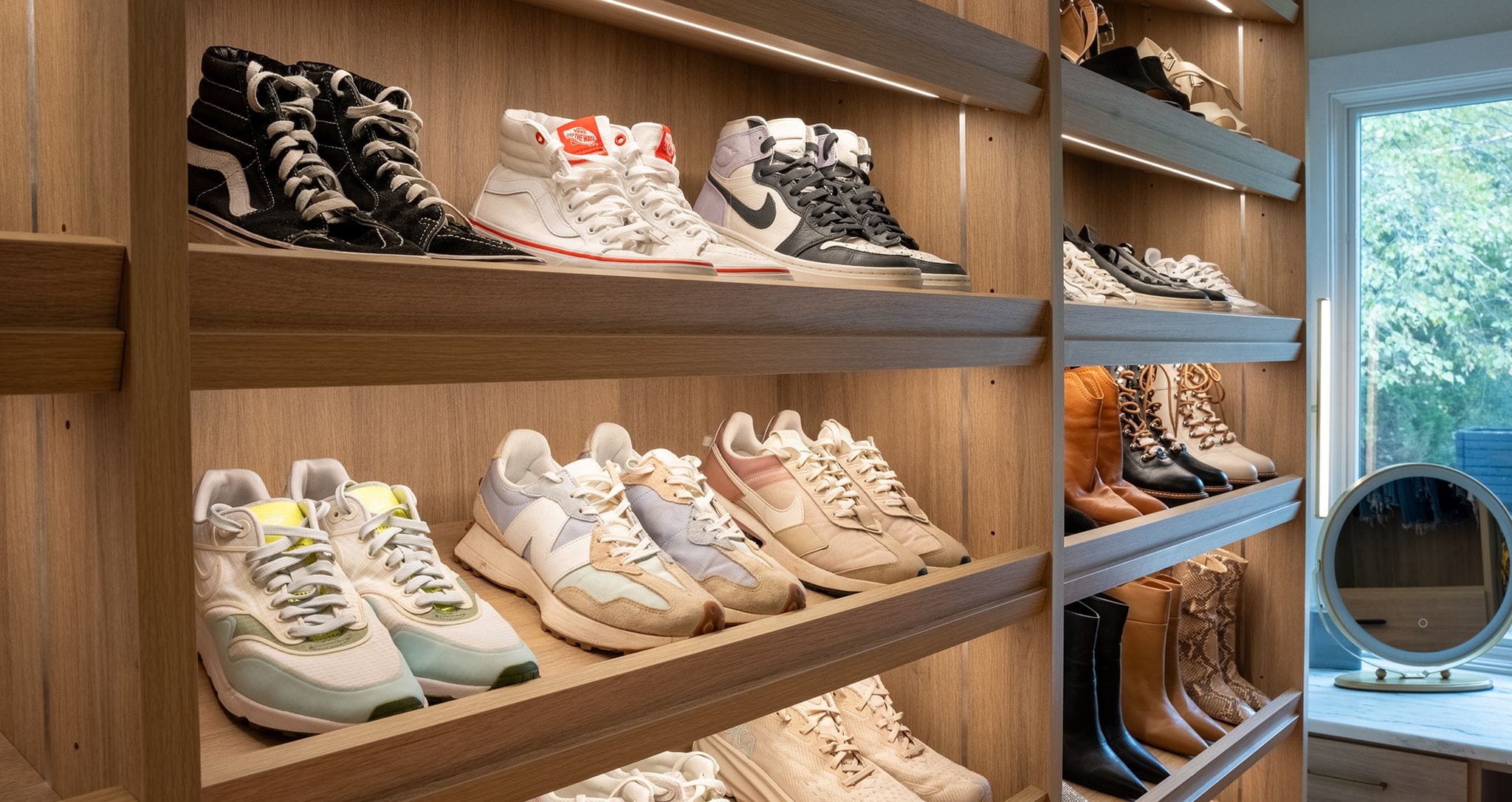 Shoe storage racks design with titled shelves and LED custom lighting in a natural wood grain finish design by California Closets