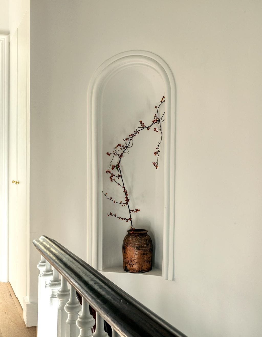 A niche in the stairwell holds an early American ceramic vessel, found in an antiques shop in upstate New York, as seen in Ideas of Order Magazine
